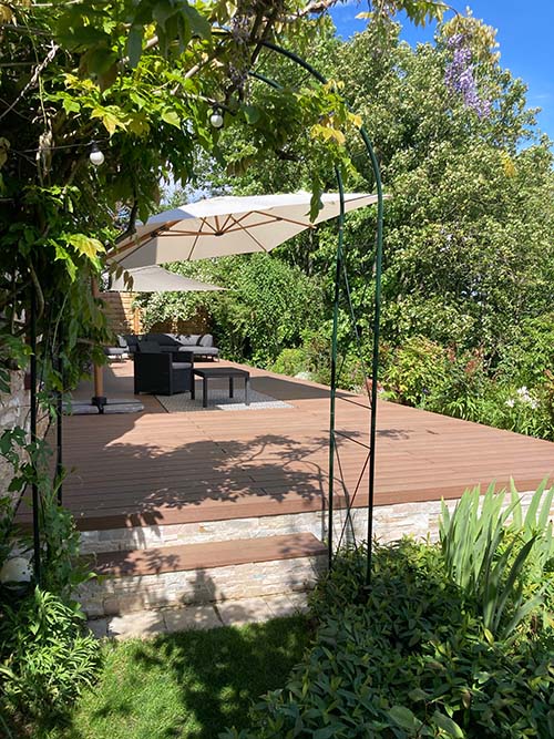 terrasse végétale pleine de plantes avec un revêtement de sol en bois composite teinte teck