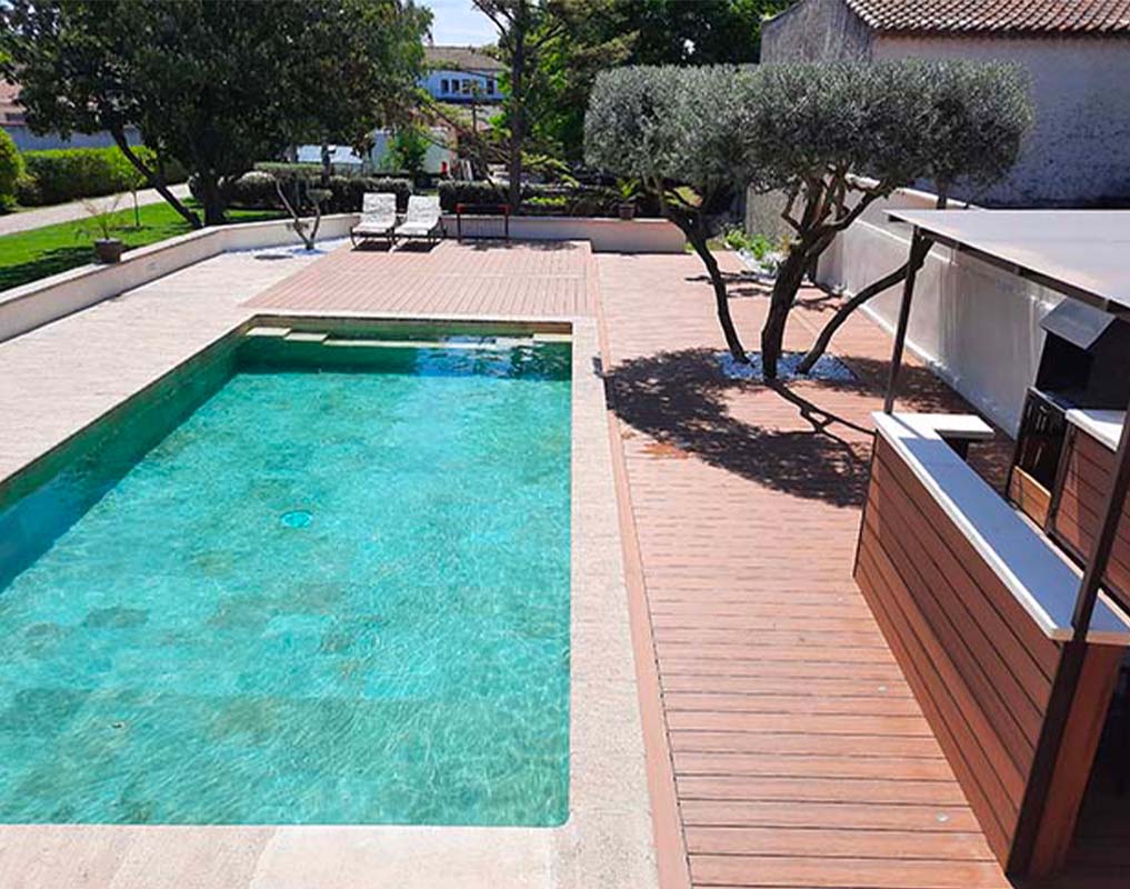 Terrasse contour de piscine en bois composite UltraProtect teinte teck et finitions structurées avec cuisine d'été